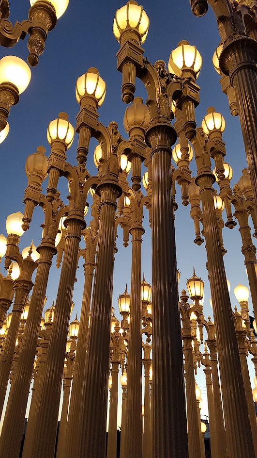 One of the most famous and free (since it is an outdoor sculpture) art you can see in the park at LACMA is the iconic Urban Lights. Created by Chris Burden, it is made of 202 restored street lamps in various styles based on where they were from (most are from southern California and some from Portland Oregon too!). The lamps are painted grey and assembled in a grid, and are solar powered and become lit in the evening.