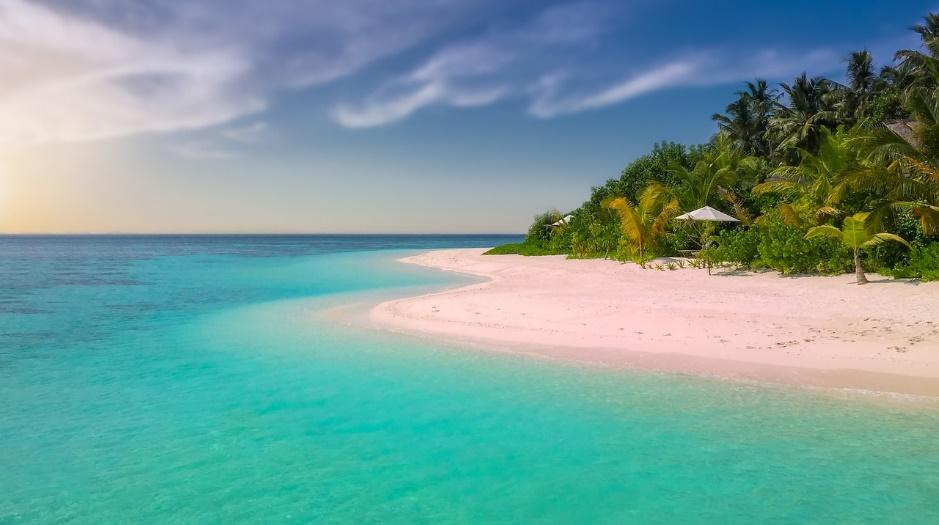 A sandy beach next to a body of water

Description automatically generated