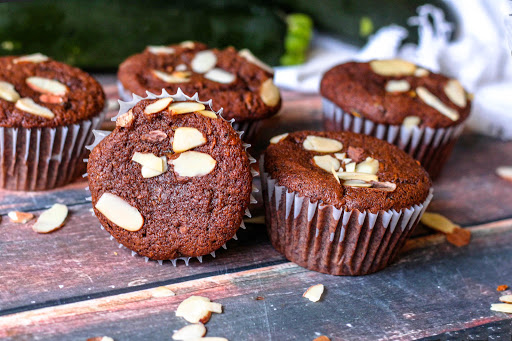 Six Chocolate Zucchini Muffins with slivered almonds on top.