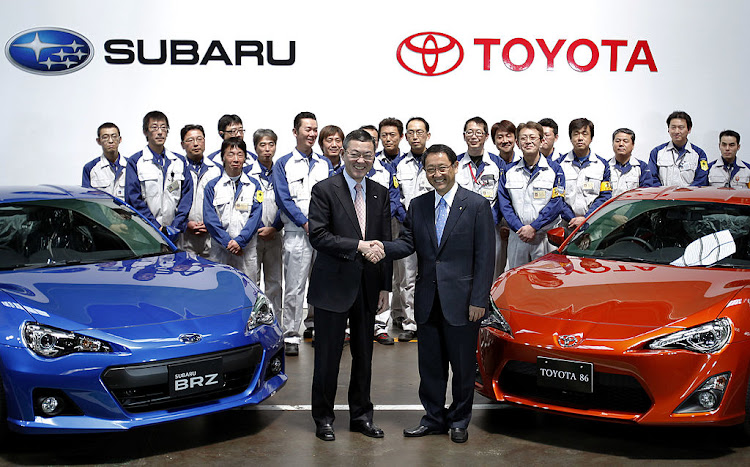 Yasuyuki Yoshinaga, president of Fuji Heavy Industries Ltd., front left, and Akio Toyoda, president of Toyota Motor Corp., shake hands as they pose for a photograph with the Subaru BRZ, left, and Toyota 86 sports coupes during a line-off ceremony at Fuji Heavy's plant in Ota City, Gunma Prefecture, Japan, on Friday, March 16, 2012.