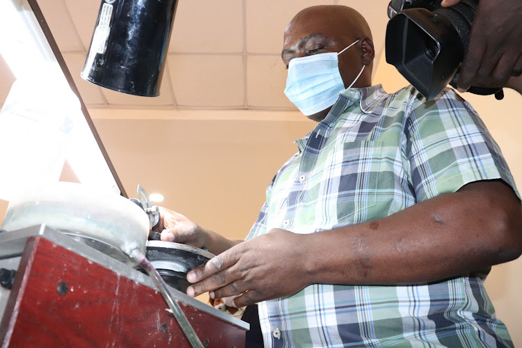 Gemstone cutter John Kibisu demonstrates how to process precious stones at the Voi Gemstone Value Addition Centre.