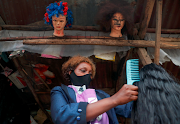 Julia Wanja, a hair stylist, combs a recycled hair extension at her makeshift hair salon near the Dandora dumpsite, amid the coronavirus disease outbreak in Eastlands Nairobi, Kenya July 29, 2020. 