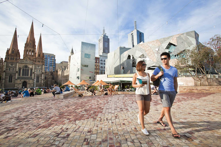 A couple walks through Federation Square in Melbourne, Australia. 