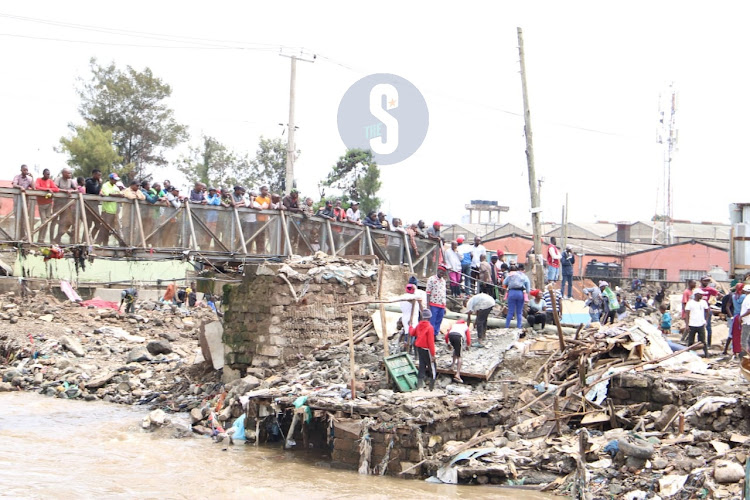 Residents watch as buildings are brought down at Mukuru kwa Reuben, Nairobi on May 6, 2024.