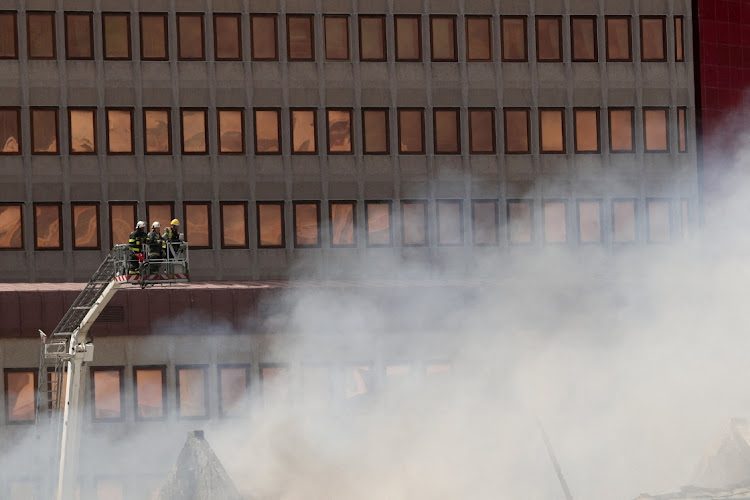 Firemen survey the damage after a fire broke out at parliament in Cape Town on January 2 2022. REUTERS/MIKE HUTCHINGS