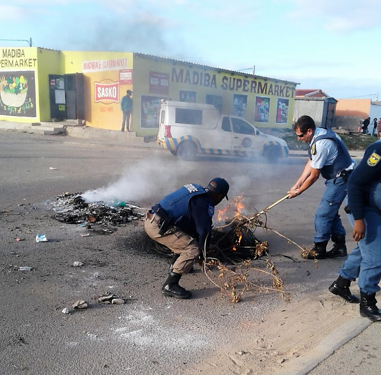 Police move rubble and burning items placed in Jijana Street, Wells Estate