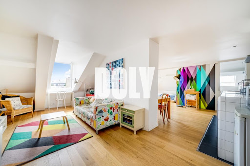 Buy this luxury property in Paris 10ème (75010) - Neighborhood Grange Aux Belles-Terrage - Bright living room with colorful sofa and geometric rug