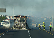 Firefighters hose down a bus set alight during a protest by taxi operators in Cape Town on Thursday.