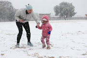 Kathrine Williams puts gloves on her daughter Katie Williams, aged 5 while they play in the snow, 10 July 2023, at Jackson Dam in Alberton, South of Johannesburg.  