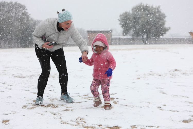 Kathrine Williams puts gloves on her daughter Katie Williams, aged 5 while they play in the snow, 10 July 2023, at Jackson Dam in Alberton, South of Johannesburg.