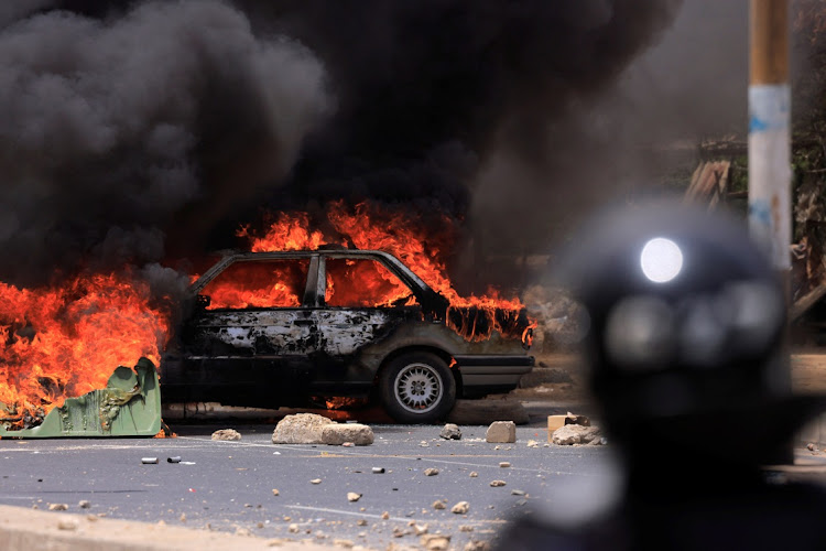 A car burns in Dakar, Senegal on June 1 2023 during clashes between security forces and students and supporters of Senegal opposition leader Ousmane Sonko after he was sentenced to prison.