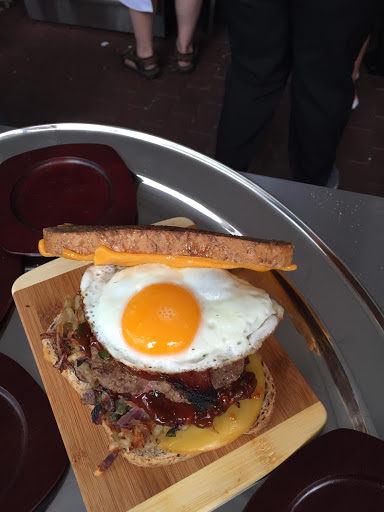 The crispy hash brown potatoes and the sunny side up egg surround the burger with spicy ketchup and cheeses.