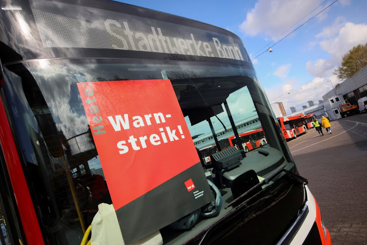 People walk near a bus with a notice behind the windshield at a storage facility during a nationwide strike called by the German trade union Verdi over a wage dispute, in Bonn, Germany, March 27, 2023. The notice reads: "Warning - strike!" Picture: WOLFGANG RATTAY/REUTERS/