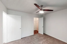 Bedroom with plush carpet, light walls, and ceiling fan