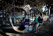 An employee of Toshimaen amusement park wearing a protective mask disinfects a seat of a wooden carousel 