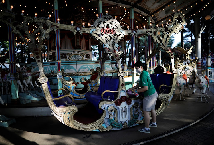 An employee of Toshimaen amusement park wearing a protective mask disinfects a seat of a wooden carousel "Carousel El Dorado" which was built in Germany in 1907 and is believed to be one of the oldest working carousels in the world.