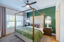 Bedroom with wood-inspired flooring, white trim, two windows with blinds, and a ceiling fan overhead 