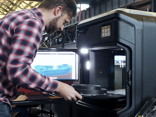 Person taking a large part out of the UltiMaker Method XL 3D Printer