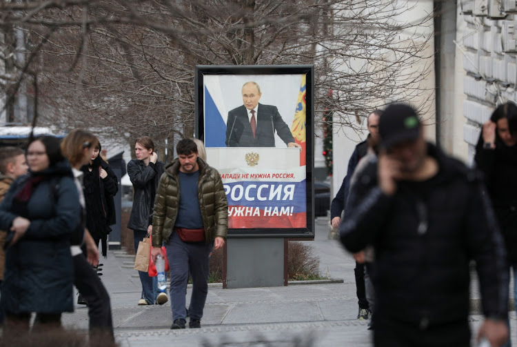 Pedestrians walk past a poster of Russian President Vladimir Putin in Sevastopol, Crimea, February 14 2024. Picture: ALEXEY PAVLISHAK/REUTERS