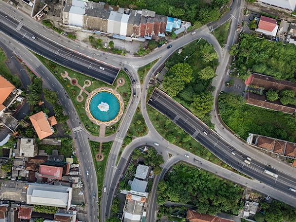 Aerial view of tree canopy intertwined with roads, parking lots, and buildings.