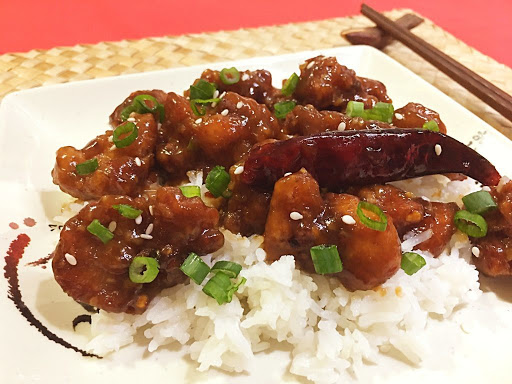 Fried chicken pieces on a bed of rice topped with green onions.