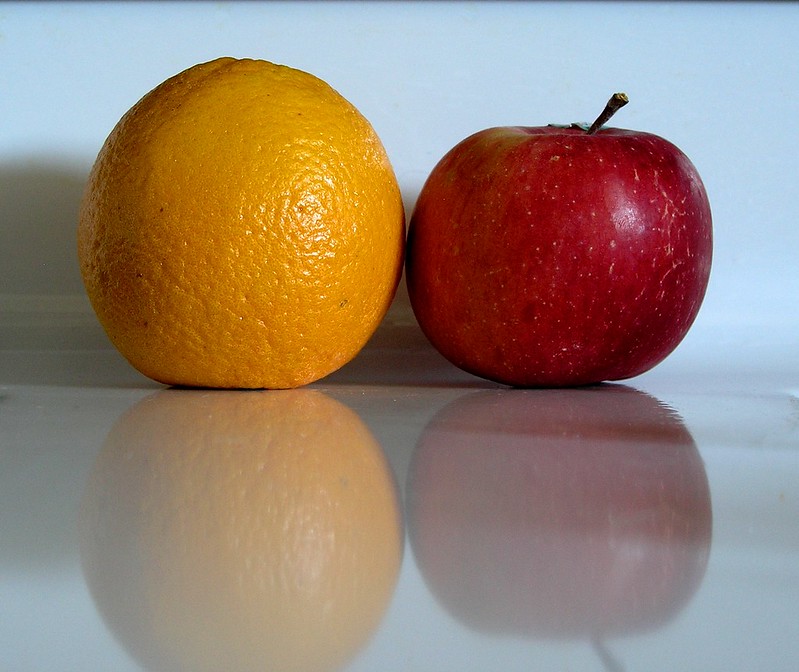 Une pomme à côté d'une orange.
