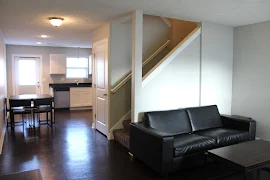 Living area with wood plank flooring open to a dining area with view of a staircase