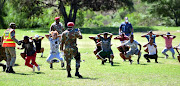 A group caught playing soccer on an open field in Helenvale, Port Elizabeth, on March 30 2020, are forced to do squats by police officers and soldiers.