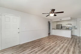 Apartment entry door open to a living area with wood plank flooring, neutral walls and white trim 