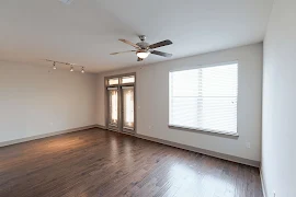 Living room featuring a large window, glass doors leading the the patio, tracking lighting, and a ceiling fan with a light