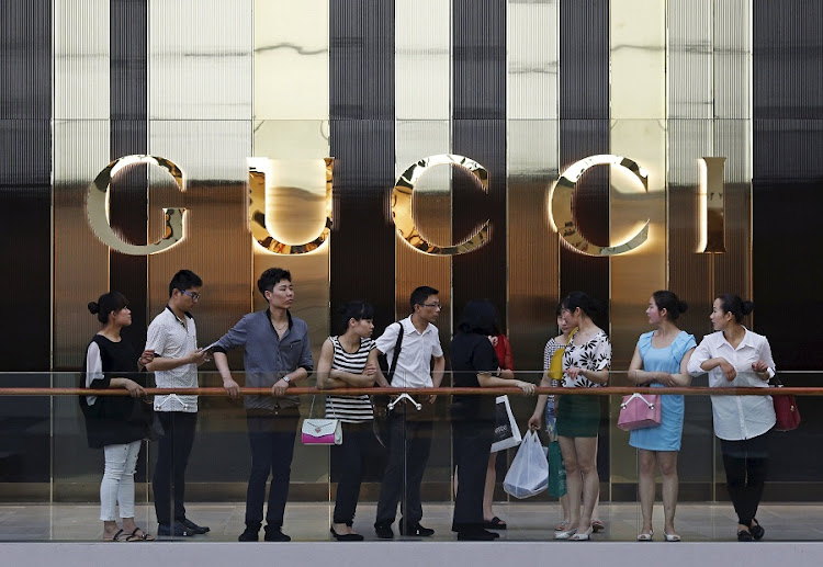 People stand outside a Gucci store. Bix luxury groups have been on a buiilding acquisition spree in top fashion locations. Picture: REUTERS/EDGAR SU