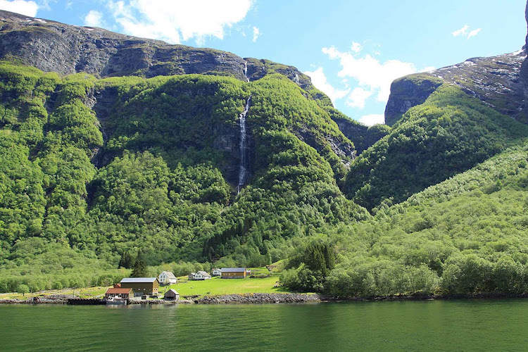 A farm on Naeroyfjord is backed by a dramatic waterfall.
