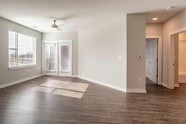 Living room with wood plank flooring, gray walls, white trim, a patio door, and a ceiling fan 