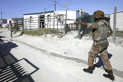 As the infection rate in Cape Town soared, a soldier in Khayelitsha orders a resident to return to his home and stay there in accordance with the regulations.