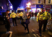 A street performer plays a musical instrument in protest against lockdown measures near police officers wearing protective face masks as pubs close ahead of the lockdown in Soho, London, Britain, November 4, 2020. 