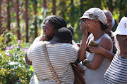 Distraught family members and residents react as a forensic pathology team removes the body of a six-year-old in White City, Soweto. Two children, aged five and six, were found mutilated this week after going missing. 