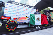 Formula 1 driver Sergio Perez poses with the Mexican flag during a press conference ahead of Mexico F1 Grand Prix at Soumaya Museum, on October 26, 2022 in Mexico City, Mexico. 
