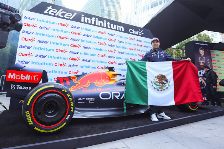 Formula 1 driver Sergio Perez poses with the Mexican flag during a press conference ahead of Mexico F1 Grand Prix at Soumaya Museum, on October 26, 2022 in Mexico City, Mexico.