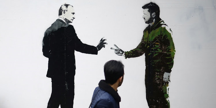 A man walks past a graffiti image showing Russian President Vladimir Putin and Ukraine President Volodymyr Zelensky. Picture: HENRY NICHOLLS/REUTERS