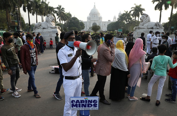 A police officer uses a megaphone to urge people to maintain social distance and to wear a face mask, as protection against Covid-19, as they gather to celebrate the arrival of the new year in front of the historic Victoria Memorial monument in Kolkata, India, on December 31 2021.