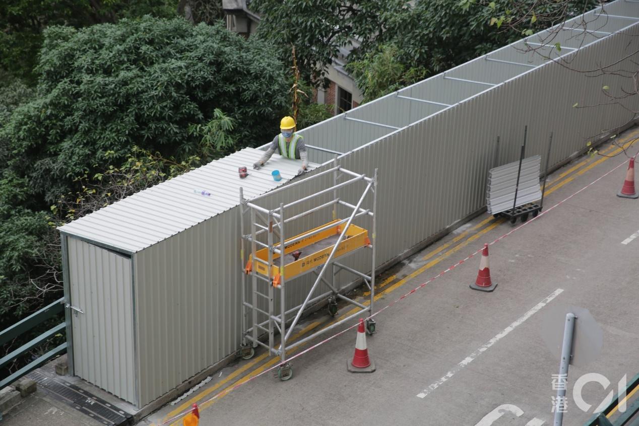 大批工人在香港大學校園內架設圍板,將寫有六四標語的太古橋行人路圍起。(黃偉民攝)