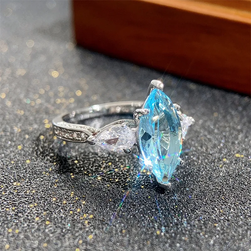 Anillo de boda con circonita azul claro en forma de ojo de caballo, incrustaciones de cobre ornamentadas, para un brillo único.