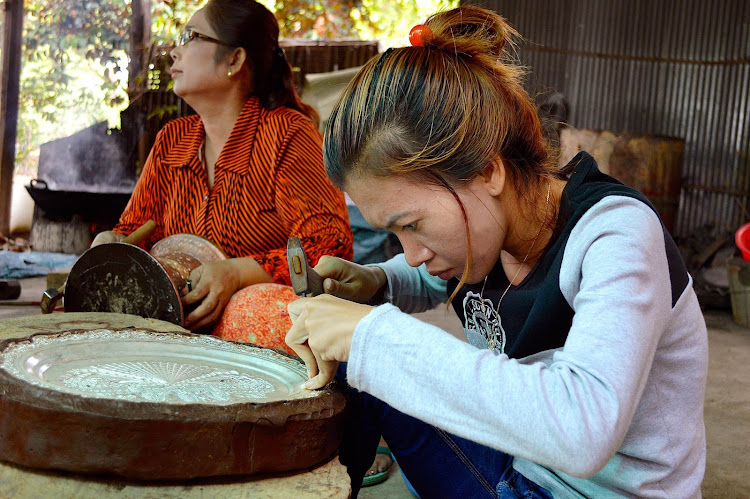 An artisan perfects a silver plate in an artisan's shop in Vietnam. 