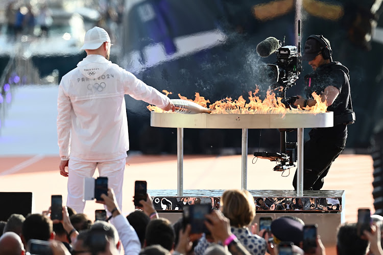 French singer JuL lights the Olympic cauldron during a ceremony welcoming the Olympic flame of Paris 2024 at the Vieux-Port (Old Port) in Marseille on May 8