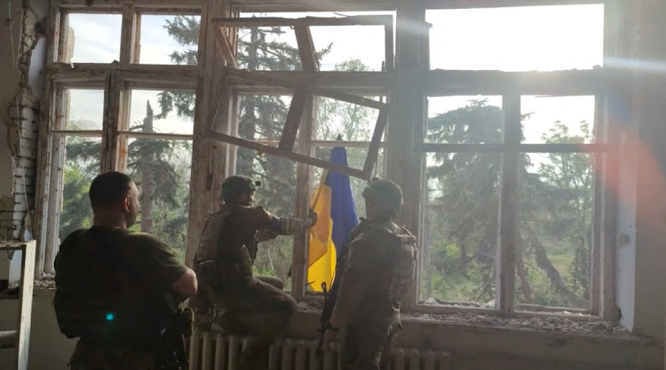 Ukrainian soldiers place a Ukrainian flag at a building in Blahodatne, Donetsk, Ukraine, in this screen shot taken from a handout video, June 11 2023. Picture: 68TH SEPARATE HUNTING BRIGADE 'OLEKSY DOVBUSHA'/REUTERS