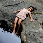 meisje ligt op rotsen met voeten in water hangend. foto: © Karolin Klüppel