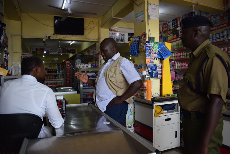 Homa Bay Nema director Josiah Nyandoro and a police officer in a supermarket in Homa Bay town on May 24, 2022