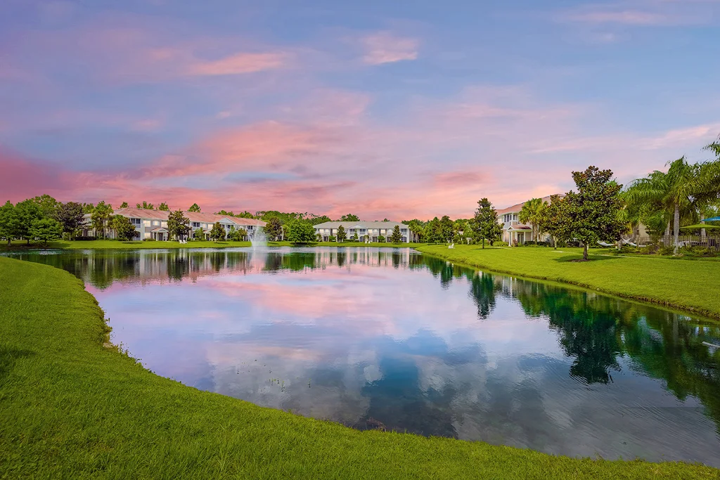 Pine Lake's on-site lake with trees and apartment buildings surrounding at dusk