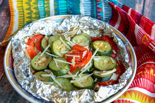 Zucchini and tomato foil packets on a plate.