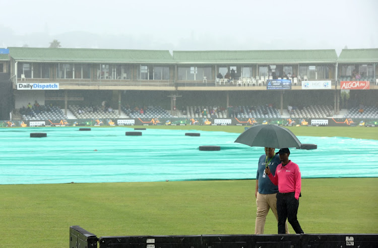 Umpire Bongani Jele holds an umbrella while inspecting the pitch before the first ODI between SA and the West Indies is called off due to rain at Buffalo Park in East London on March 16 2023.